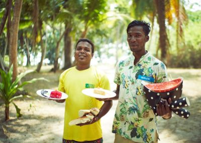 Munjoh staff-two males holdig a plate with fruits and cakes