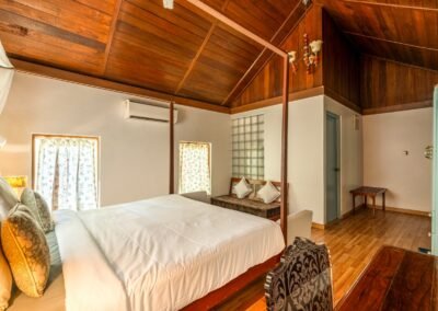 King four-poster bedroom with wooden flooring inside the Royal Chalet at Munjoh Ocean Resort