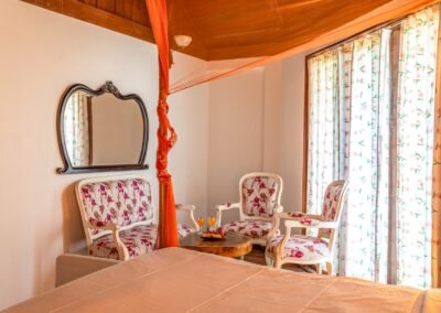 Four-poster bedroom with a window-side seating area in the Royal Chalet at Munjoh Ocean Resort