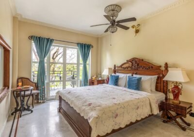 Emerald Suite bedroom with carved wooden bed and balcony doors at Munjoh Island House in Port Blair