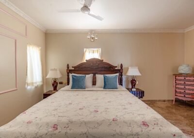 Bedroom with carved wooden bed and soft pink detailing in Kohinoor Residence at Munjoh Island House