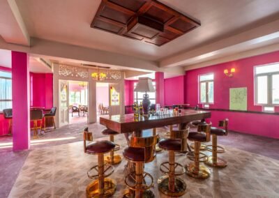 Pink bar interior with wooden counter and stools at The Port, Munjoh Island House, Port Blair